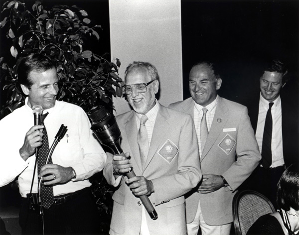 Ceremonies producer David Wolper holds the torch used by Rafer Johnson to light the Coliseum cauldron with, from left, Peter Ueberroth, John C. Argue and Harry Usher.
